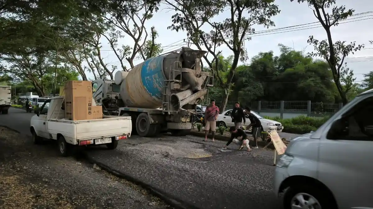 Warga melintas di ruas Jalan Ir Soekarno Minut yang berlubang