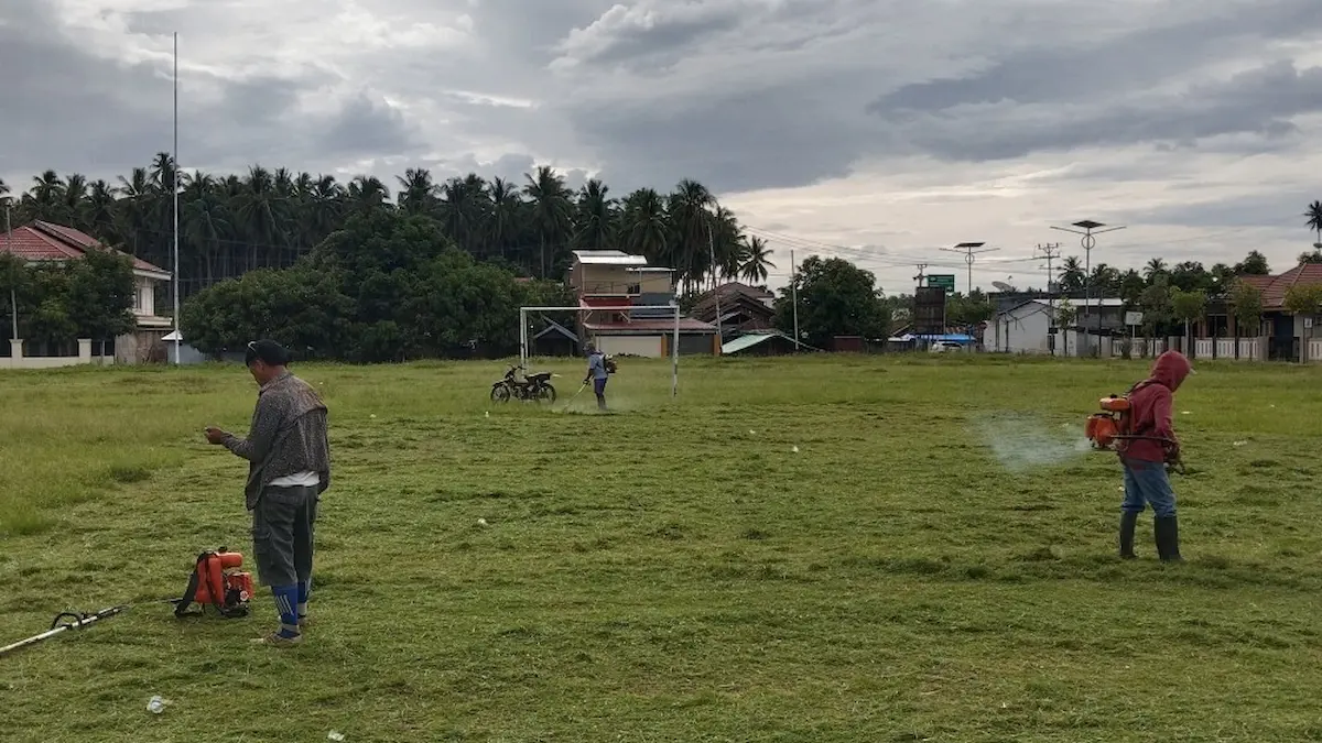 warga dan aparatur boltim potong rumput lapangan desa jumat asri
